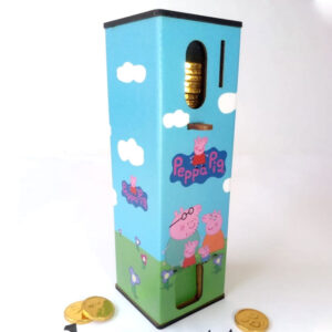 Alcancía dispensadora de monedas de chocolate con diseño de pepa pig, está la familia sobre un fondo con cielo azul y cesped color verde.